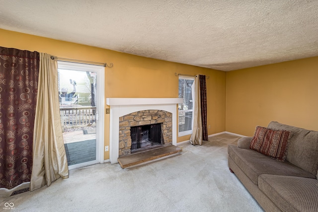 living area with a stone fireplace, carpet, baseboards, and a textured ceiling