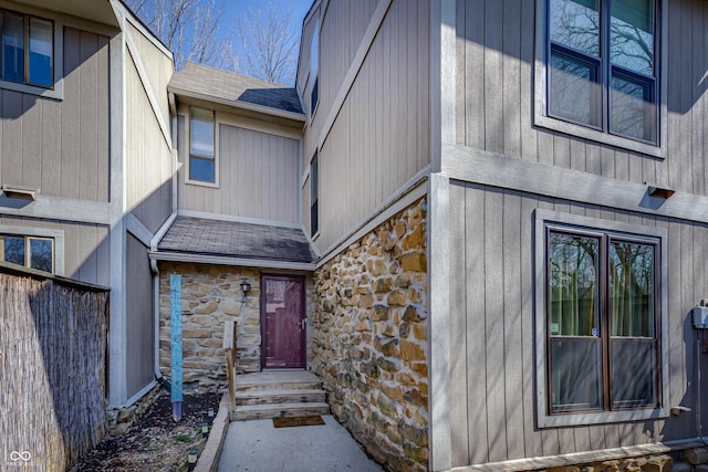 property entrance with stone siding and a shingled roof