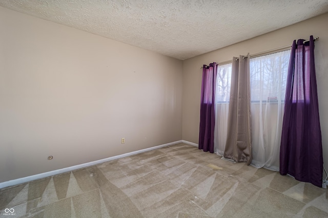 unfurnished room with light carpet, a textured ceiling, and baseboards