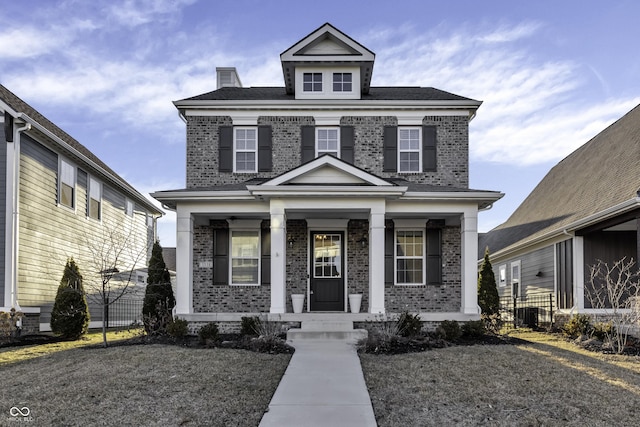 american foursquare style home featuring a porch and brick siding