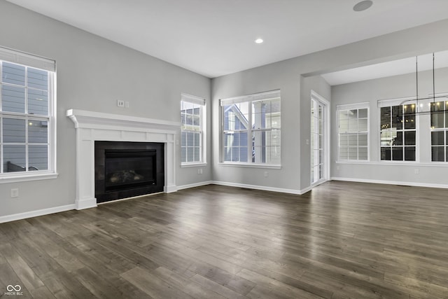 unfurnished living room with a glass covered fireplace, recessed lighting, dark wood finished floors, and baseboards