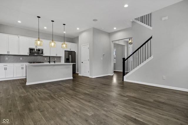 kitchen with stainless steel appliances, decorative backsplash, dark wood-type flooring, white cabinetry, and open floor plan