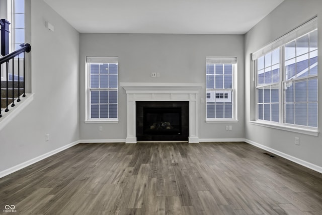 unfurnished living room featuring stairs, dark wood-type flooring, visible vents, and baseboards