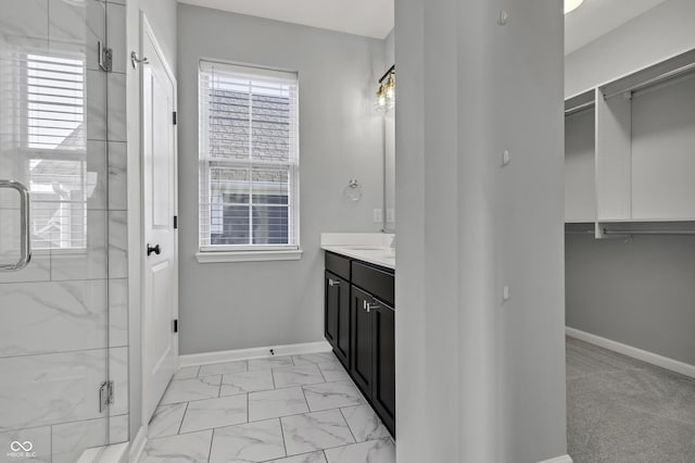 bathroom with marble finish floor, vanity, a shower stall, and baseboards