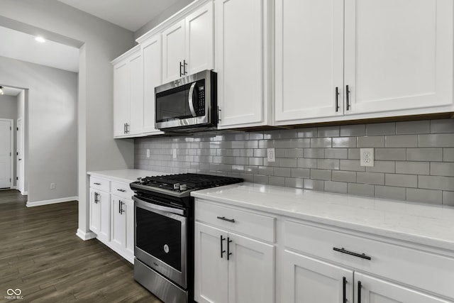 kitchen featuring tasteful backsplash, dark wood-type flooring, light stone countertops, appliances with stainless steel finishes, and white cabinetry