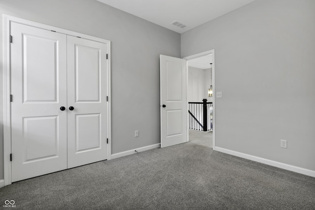 unfurnished bedroom with a closet, visible vents, baseboards, and carpet