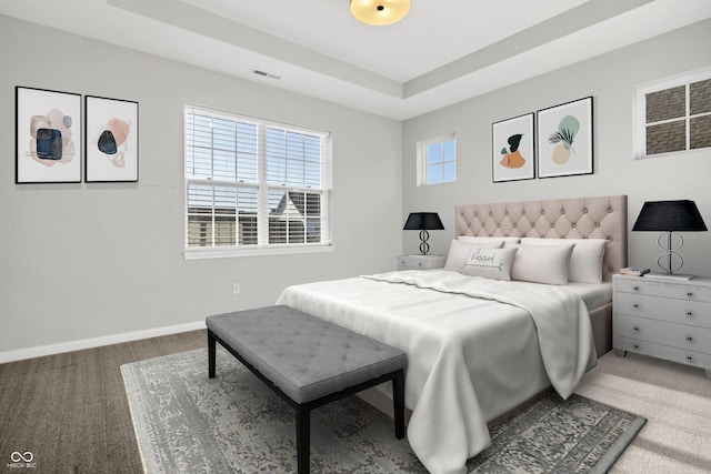 carpeted bedroom featuring baseboards, a raised ceiling, and visible vents