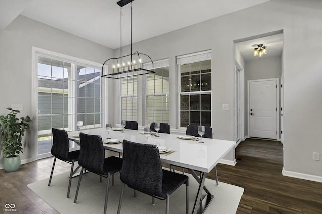 dining room with dark wood-type flooring, a notable chandelier, and baseboards