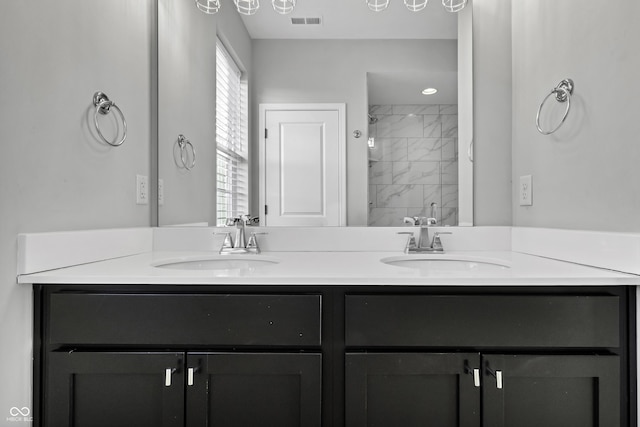 full bath with double vanity, visible vents, tiled shower, and a sink