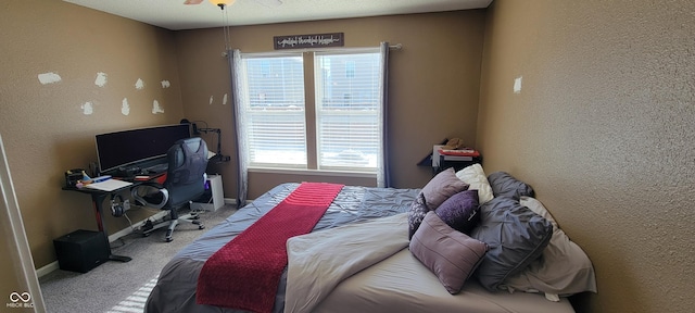 bedroom featuring a ceiling fan, light colored carpet, a textured wall, and baseboards