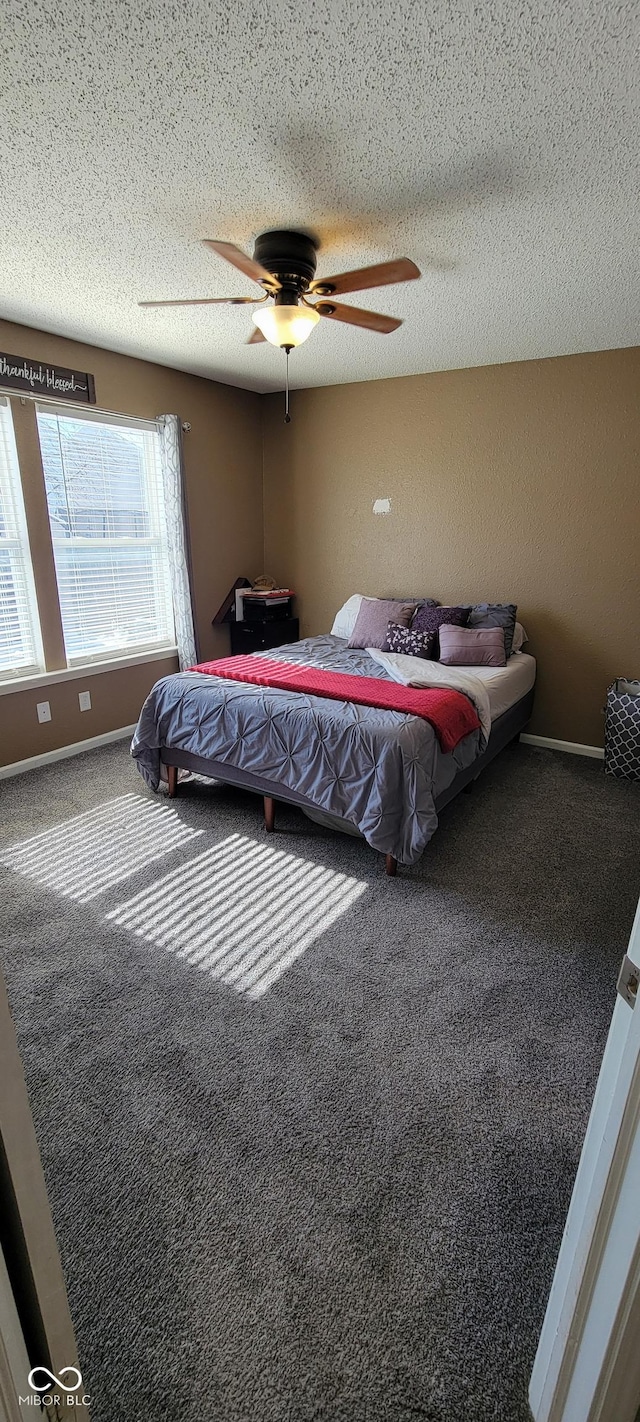 carpeted bedroom featuring a ceiling fan, a textured ceiling, and baseboards