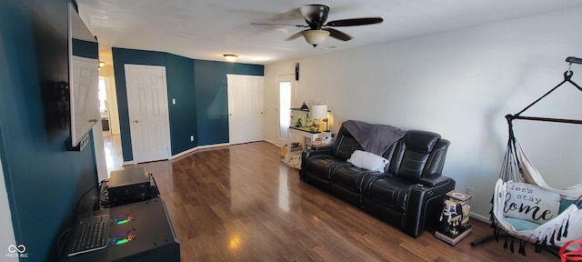 living area featuring ceiling fan, baseboards, and wood finished floors