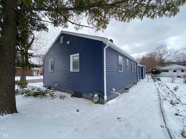 view of snowy exterior with a garage and a chimney