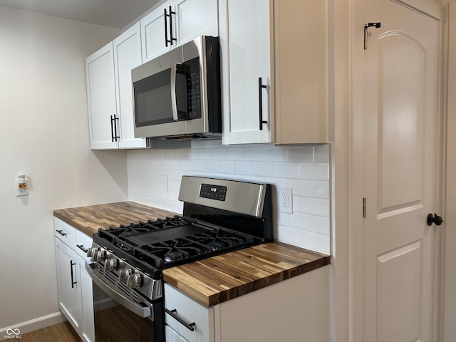 kitchen with appliances with stainless steel finishes, butcher block counters, white cabinetry, and backsplash