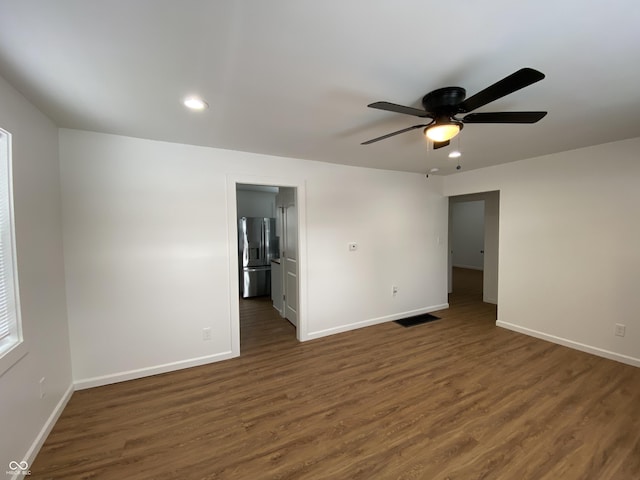 empty room featuring dark wood-style floors, visible vents, and baseboards