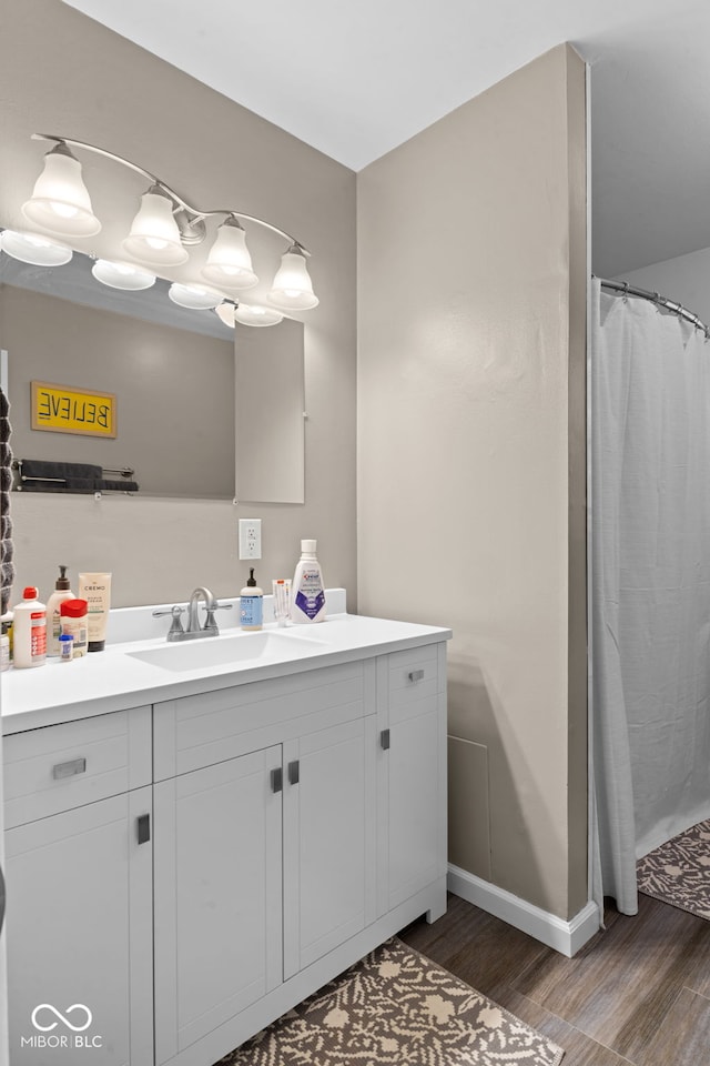 full bath featuring vanity, baseboards, and wood finished floors