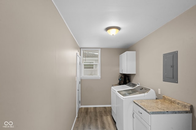 laundry room featuring washing machine and clothes dryer, cabinet space, light wood-style floors, electric panel, and baseboards