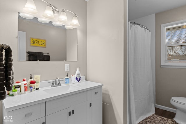 bathroom with toilet, wood finished floors, vanity, and baseboards