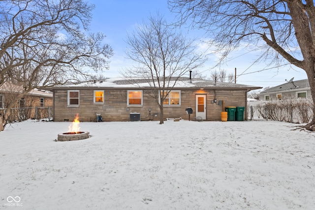 snow covered back of property with fence, a fire pit, and central AC unit