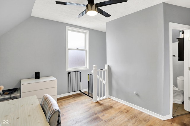 interior space with a textured ceiling, light wood finished floors, lofted ceiling, and baseboards