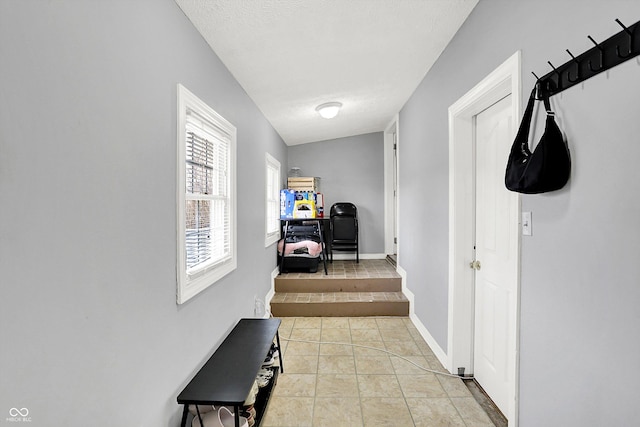 hall featuring baseboards and light tile patterned floors