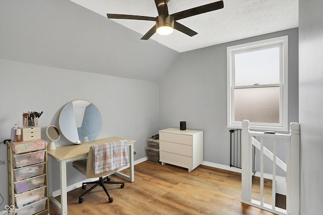 office featuring lofted ceiling, a textured ceiling, a ceiling fan, baseboards, and light wood finished floors