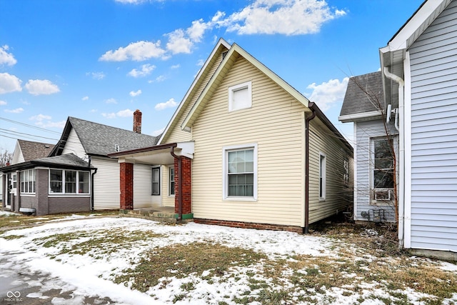 snow covered back of property with a shingled roof