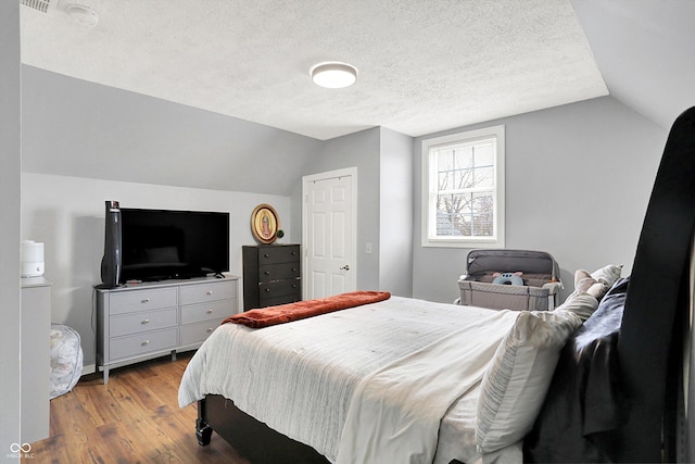 bedroom featuring a textured ceiling, wood finished floors, and lofted ceiling