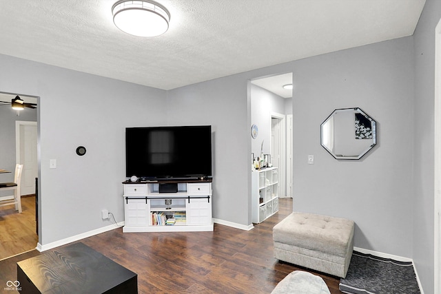 living room with a textured ceiling, baseboards, and wood finished floors