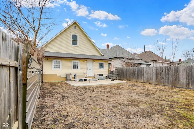 rear view of house featuring entry steps, a chimney, a patio area, and a fenced backyard