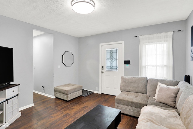 living room featuring dark wood-style floors, a textured ceiling, and baseboards