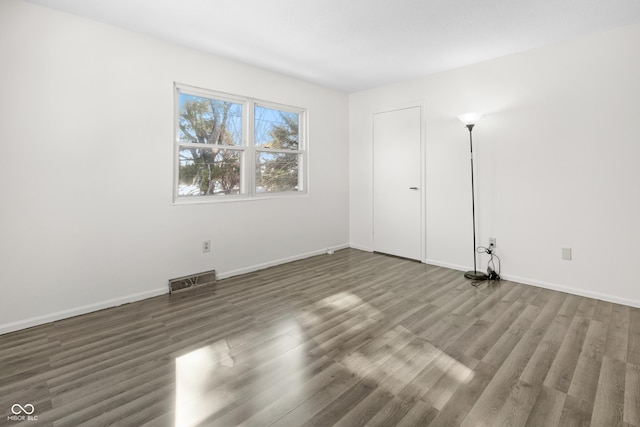 unfurnished bedroom with dark wood-style floors, baseboards, and visible vents