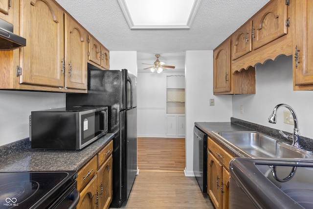 kitchen featuring dark countertops, brown cabinets, dishwasher, and under cabinet range hood