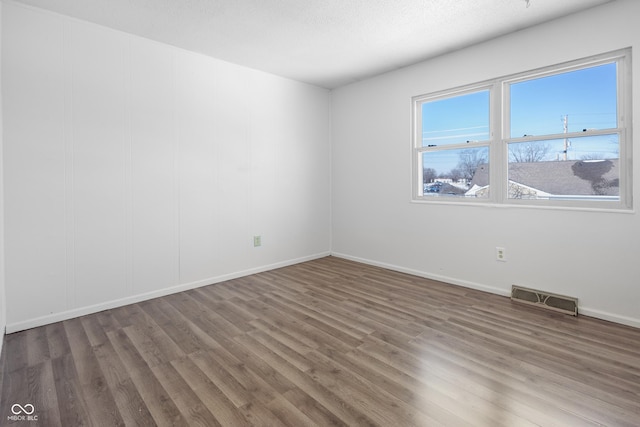 spare room featuring dark wood-style floors, baseboards, visible vents, and a textured ceiling