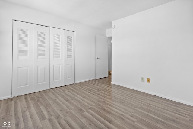 unfurnished bedroom featuring a closet, light wood-style flooring, and baseboards