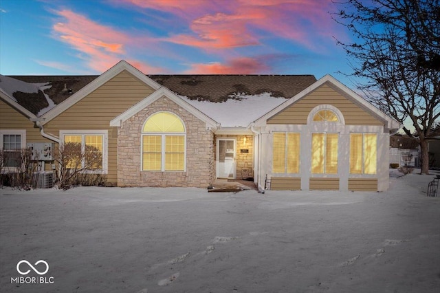 back of property with stone siding and central AC unit