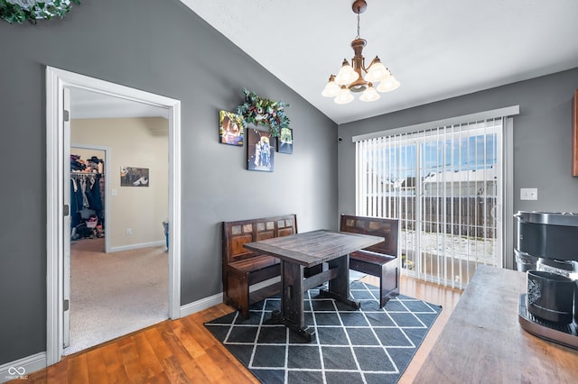 dining area with baseboards, a chandelier, vaulted ceiling, and dark wood-type flooring