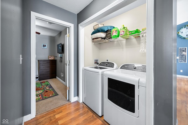 laundry room featuring laundry area, light wood-type flooring, washing machine and dryer, and baseboards