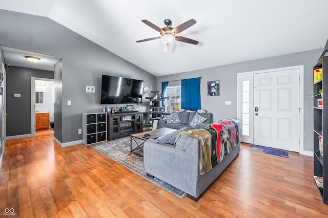 living room with a ceiling fan, baseboards, vaulted ceiling, and wood finished floors