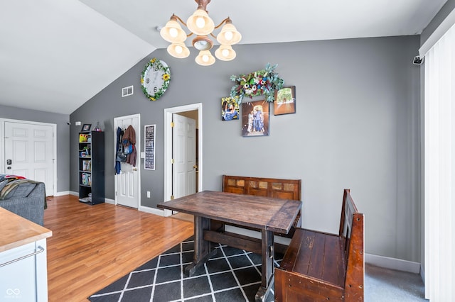 dining space with a notable chandelier, lofted ceiling, visible vents, wood finished floors, and baseboards