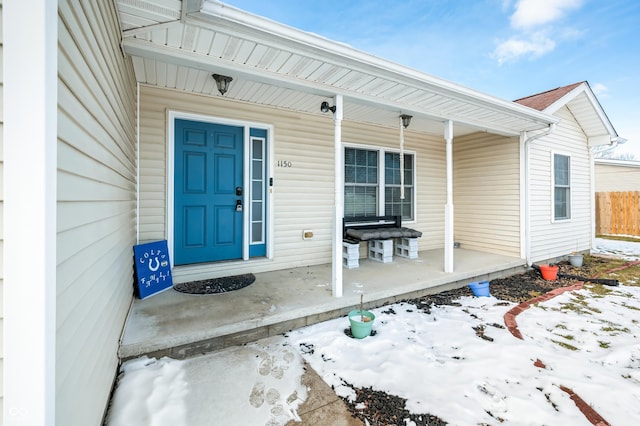 snow covered property entrance with covered porch