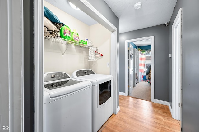 clothes washing area with light wood-style floors, washing machine and dryer, laundry area, and baseboards