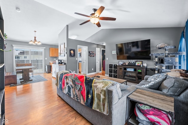 living area featuring light wood-type flooring, vaulted ceiling, and ceiling fan with notable chandelier