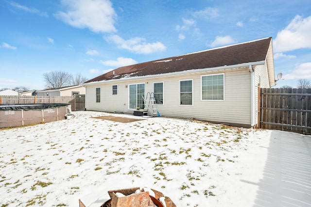 snow covered back of property featuring a fenced in pool