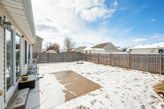 yard layered in snow with a patio area and a fenced backyard