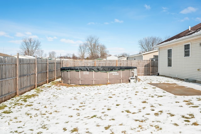 yard layered in snow featuring a fenced in pool and a fenced backyard