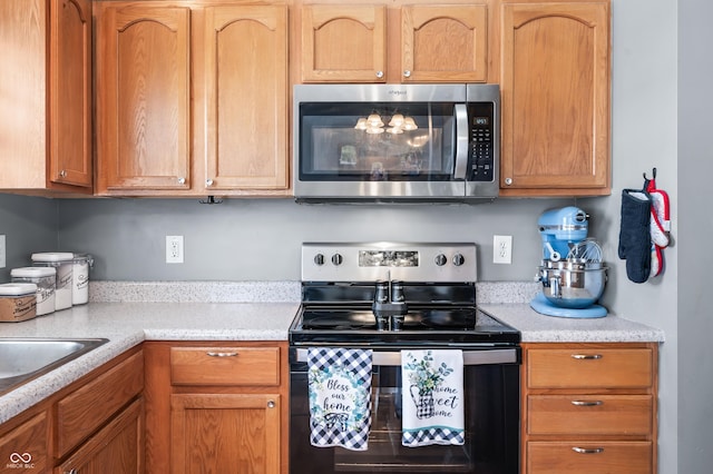 kitchen with light countertops, electric stove, stainless steel microwave, and a sink