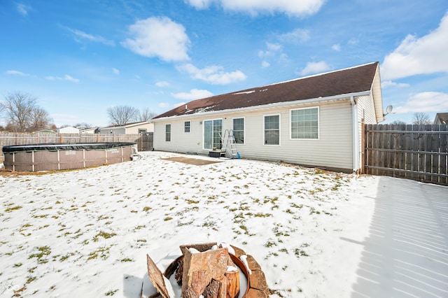 snow covered rear of property featuring a fenced in pool