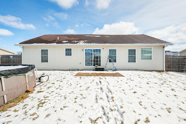 snow covered house with fence and a fenced in pool