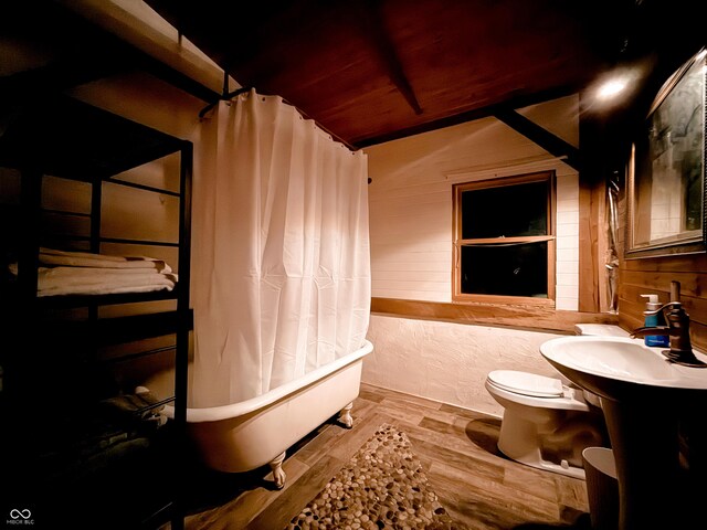 bathroom with toilet, shower / tub combo, wooden walls, and wood finished floors